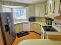 Galley kitchen with wood cabinets, stainless steel appliances, and laminate flooring at 12501 Ulmerton Rd # 188, Largo, FL 33774