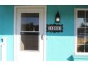 Charming aqua home exterior with decorative house number plaque and white-framed entry door with screen at 1322 Kenmore St, Port Charlotte, FL 33952