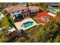 Expansive backyard with a pool, lounging areas, a firepit, mature trees, and lovely landscaping at 403 Weeburn Rd, Temple Terrace, FL 33617