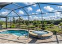 Screened-in pool and spa featuring brick pavers and lush landscaping at 4748 Ballast Crest Cv, Land O Lakes, FL 34638