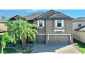 Two-story house with gray siding, palm trees, and a brick driveway at 9919 Smarty Jones Dr, Ruskin, FL 33573