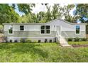 Mobile home with light gray siding, new landscaping, and steps leading to the entrance at 13017 Manatee Ave, New Port Richey, FL 34654