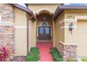 Inviting front entrance showcasing double doors, stone accents, manicured greenery, and a vibrant red walkway at 6722 Boulder Run Loop, Wesley Chapel, FL 33545