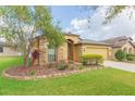 Single-Gathering home featuring a well-manicured lawn, colorful landscaping, and an attached two-car garage at 6722 Boulder Run Loop, Wesley Chapel, FL 33545