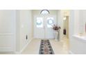 Bright foyer featuring tile flooring, a decorative rug, and an elegant double-door entrance with transom window at 6722 Boulder Run Loop, Wesley Chapel, FL 33545