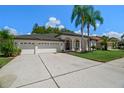 White house with dark brown roof, 3-car garage, and palm trees at 1257 Kings Way Ln, Tarpon Springs, FL 34688