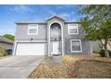 Two-story house with gray exterior, arched entryway, and white garage door at 1703 Alhambra Crest Dr, Ruskin, FL 33570