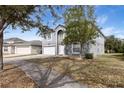 Gray two-story house with a white door and attached garage, nestled amongst trees at 1703 Alhambra Crest Dr, Ruskin, FL 33570