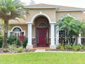 House with a red door, three columns, and well-manicured lawn at 3011 Marble Crest Dr, Land O Lakes, FL 34638