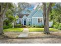 Beautiful, bright blue bungalow with green lawn, lovely landscaping and mature shade trees at 828 17Th N Ave, St Petersburg, FL 33704