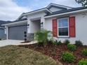 Newly built home with gray siding, red shutters, and a palm tree at 13154 Kent Bradley Glade Rd, Dade City, FL 33525