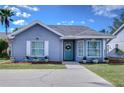 Charming single-story home featuring a welcoming blue door, bright windows, and a well-manicured front yard at 13908 Orange Dale Pl, Tampa, FL 33625