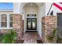 Welcoming front entrance boasting stone pillars and double doors with glass inserts and wreaths at 15110 Shearcrest Dr, Lithia, FL 33547