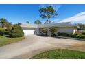 White brick ranch home with circular driveway and mature landscaping at 2389 Sarazen Dr, Dunedin, FL 34698