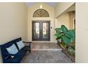 Elegant entryway with double doors, a bench, and lush tropical plants at 3312 Cobbs Ct, Palm Harbor, FL 34684