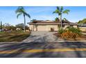 Street view of a single story home featuring a 2-car garage, palm trees, meticulous landscaping and a concrete driveway at 4001 Harbor Hills Dr, Largo, FL 33770