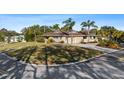 Charming single story home featuring a circular driveway, large front lawn, and beautiful landscaping with palm trees at 4001 Harbor Hills Dr, Largo, FL 33770