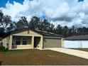 Tan house with gray garage door, solar panels, and a white fence at 8303 Begonia St, Spring Hill, FL 34608