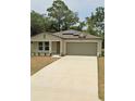 Tan house with gray garage door and solar panels at 8303 Begonia St, Spring Hill, FL 34608