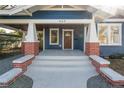 Quaint front porch with brick columns and a wood front door at 409 E Adalee St, Tampa, FL 33603