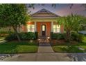 Evening view of a charming one-story home with a peach-colored facade and front porch at 5200 Suncatcher Dr, Wesley Chapel, FL 33545