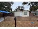 Charming single-story home featuring a decorative front door, textured walls, a fenced yard, and a mailbox at 8014 N Alaska St, Tampa, FL 33604