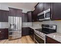 Kitchen with dark wood cabinets, granite counters, and stainless steel appliances at 2413 Baywood E Dr, Dunedin, FL 34698