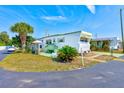 White mobile home with a green lawn, palm trees, and a parked car at 27466 Us Highway 19 N # 54, Clearwater, FL 33761