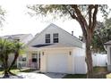 Charming two-story home featuring a light yellow exterior, single car garage, and a cozy front porch with rocking chairs at 5607 Tanagergrove Way, Lithia, FL 33547