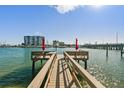 Wooden dock extending into calm water with red umbrellas at 9715 Harrell Ave # 25, Treasure Island, FL 33706