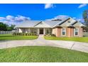 Charming home showcasing a manicured lawn and circular driveway, surrounded by lush landscaping at 1702 W Knights Griffin Rd, Plant City, FL 33565