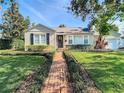 Beautifully landscaped front yard with lush green lawn, charming brick path, and cozy curb appeal at 212 S Himes Ave, Tampa, FL 33609