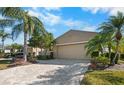 Tan two-car garage villa with paver driveway and mature landscaping at 2416 Kensington Greens Dr # 2416, Sun City Center, FL 33573