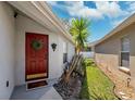 Inviting front entrance with a red door and decorative wreath, set amongst manicured landscaping at 31806 Larkenheath Dr, Wesley Chapel, FL 33543