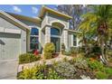 Charming home featuring lush landscaping, a beautiful entryway, and a well-maintained lawn at 3710 Rain Tree Ct, Palm Harbor, FL 34685