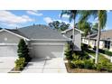 Two-story house with gray exterior, two-car garage, and palm trees at 1252 Lyndhurst Greens Dr, Sun City Center, FL 33573