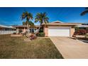 Tan house with white garage door and palm trees at 14993 Imperial Point N Dr, Largo, FL 33774