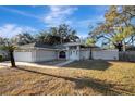 Two-car garage, gray house with white front door, and a palm tree in the front yard at 2733 Glenview Dr, Land O Lakes, FL 34639