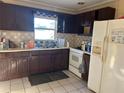 Basic kitchen with dark cabinets, white appliances, and checkered tile at 5163 Jasmine Cir, St Petersburg, FL 33714