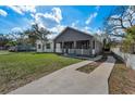 Inviting single-story home showcasing a well-manicured lawn, a classic porch and a private driveway at 8716 N Brooks St, Tampa, FL 33604