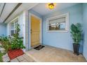 Light yellow front door with tiled entryway and landscaping at 10 N Mercury Ave, Clearwater, FL 33765