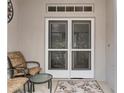 Inviting covered front porch featuring seating and decorative glass on double entry doors at 11121 Sun Tree Rd, Hudson, FL 34667