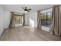 Bright bedroom with wood-look floors, ceiling fan, and two windows with blinds and curtains at 3377 Crystal E Ct # E, Palm Harbor, FL 34685