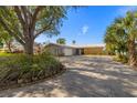 Charming single-story home with a well-manicured lawn, mature trees, and a spacious driveway at 521 Harbor N Dr, Indian Rocks Beach, FL 33785