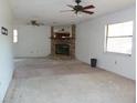 Bright living room featuring a brick fireplace, two ceiling fans, and natural lighting through two windows at 6567 S West Shore Cir, Tampa, FL 33616