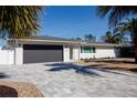 Well-manicured home featuring a sleek gray garage door, paved driveway, and lush front yard at 4523 Clearwater Harbor S Dr, Largo, FL 33770