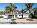 Charming home with modern curb appeal, a gray driveway, and tropical landscaping with palm trees at 4523 Clearwater Harbor S Dr, Largo, FL 33770
