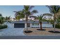 Charming home with modern curb appeal, a gray driveway, and tropical landscaping with palm trees at 4523 Clearwater Harbor S Dr, Largo, FL 33770