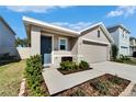 Tan house with gray door, two-car garage, and well-maintained yard at 5322 Fiddle Fig Ave, Wimauma, FL 33598