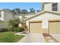 Attractive townhouse featuring a two-car garage, healthy green lawn, and freshly trimmed shrubs at 2938 Royal Tuscan Ln, Valrico, FL 33594